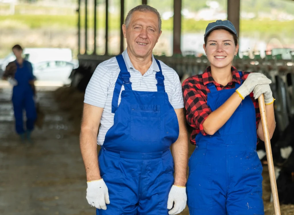 Un salarié agricole et une jeune salariée en élevage posent dans une exploitation laitière moderne, illustrant l’évolution de l’emploi agricole avec la hausse du salariat et le recul des exploitants non salariés.