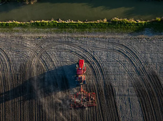 Photo d'un tracteur Case IH dans un champ proche d'un cours d'eau