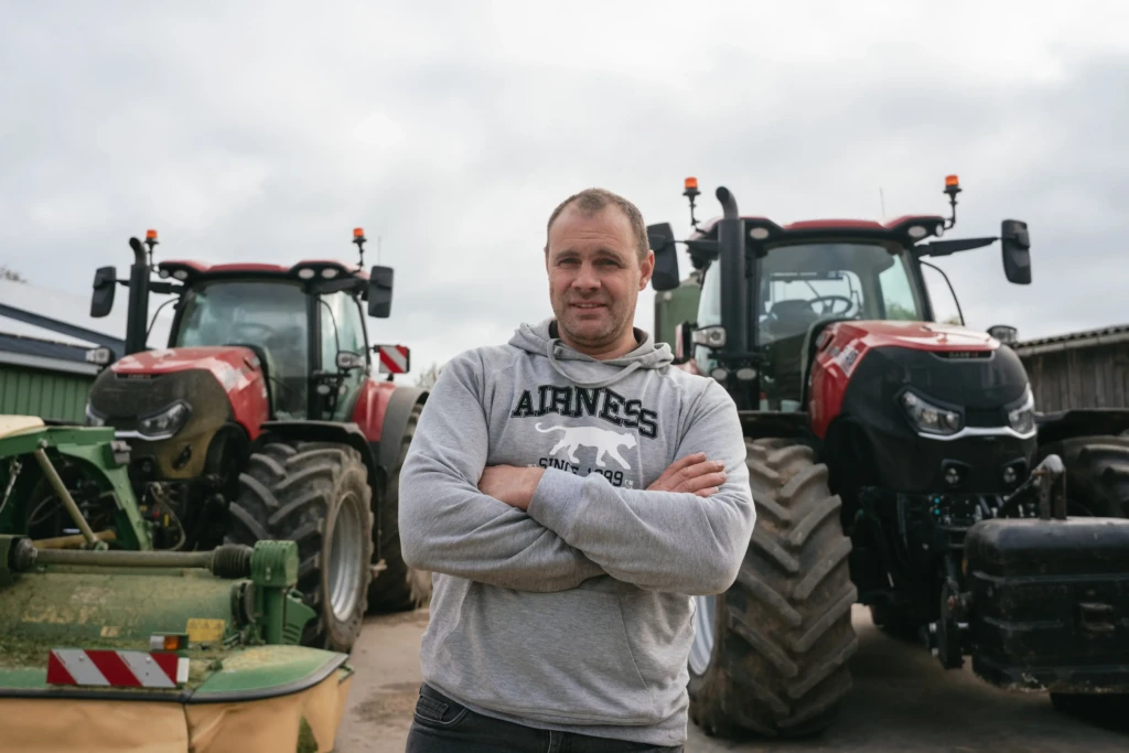 Photo d'un des associés de la ferme des moulins de Kerollet devant des tracteurs Case IH 